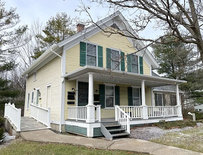 Yellow clapboard house with porch supported by white columns.